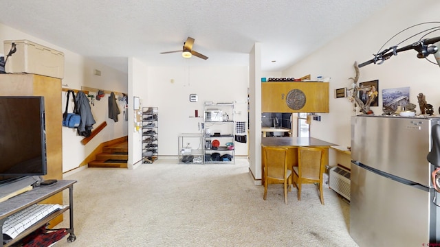 interior space with a ceiling fan, freestanding refrigerator, light colored carpet, and a textured ceiling