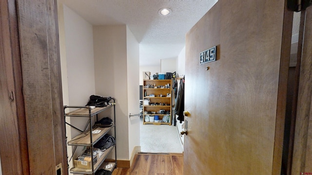 corridor featuring a textured ceiling and wood finished floors