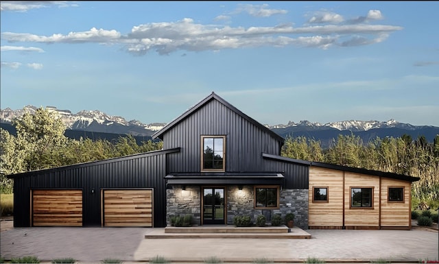 view of front facade with decorative driveway, an attached garage, board and batten siding, and a mountain view