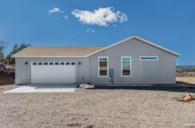 view of front facade with a garage, roof with shingles, and gravel driveway