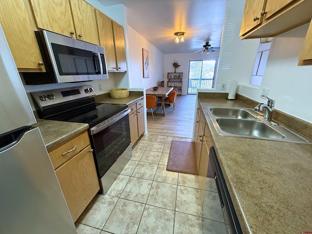 kitchen with brown cabinetry, a ceiling fan, appliances with stainless steel finishes, a sink, and light tile patterned flooring