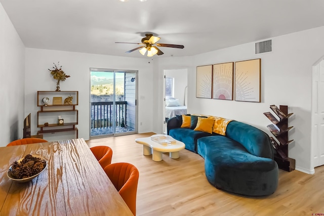 living room featuring baseboards, wood finished floors, visible vents, and a ceiling fan