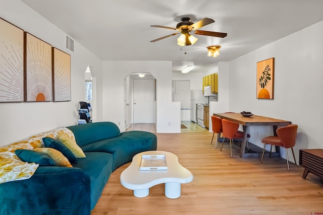 living room with a ceiling fan, arched walkways, visible vents, and light wood-style flooring