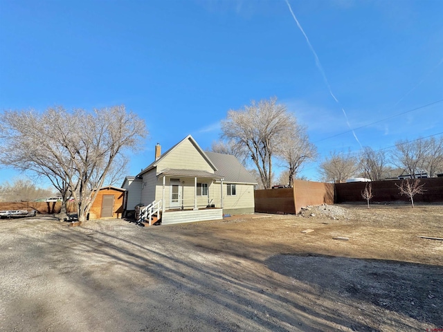 view of front of home with an outbuilding, fence, and a chimney