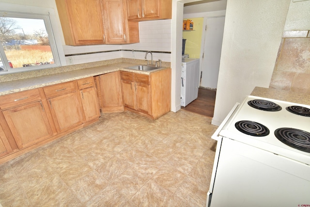 kitchen with a sink, electric stove, light countertops, washer / clothes dryer, and tasteful backsplash