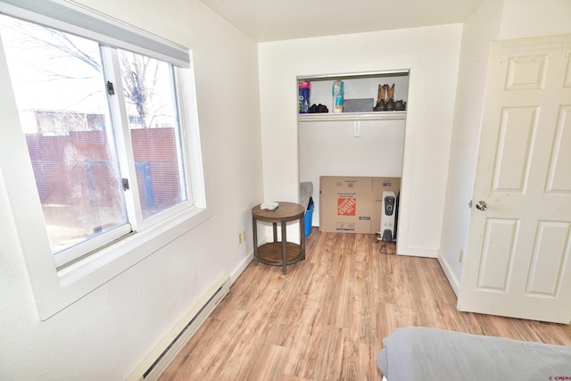 sitting room with light wood-type flooring, baseboards, and baseboard heating