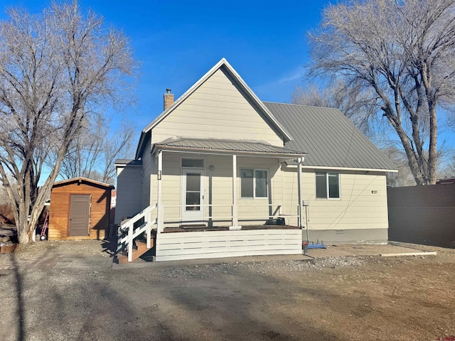 view of front of home featuring metal roof, a porch, an outdoor structure, crawl space, and a shed