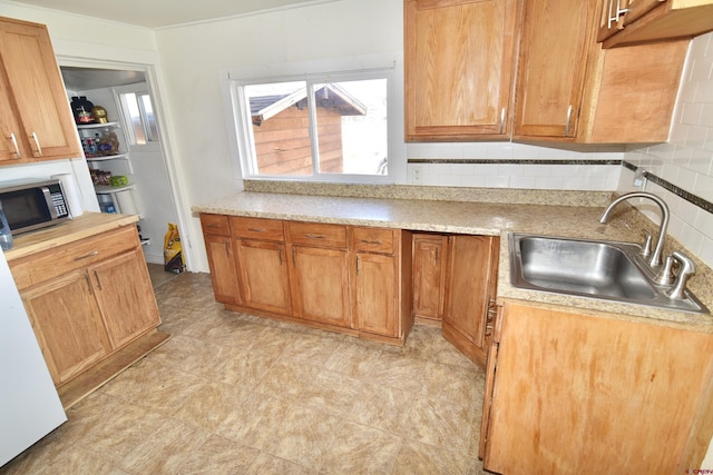 kitchen featuring light countertops, tasteful backsplash, stainless steel microwave, and a sink