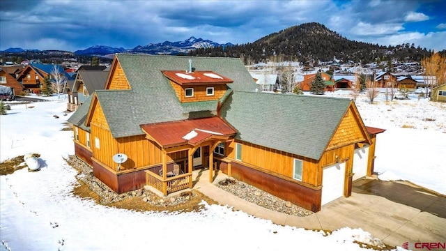 view of front of property with a residential view, roof with shingles, a mountain view, and driveway