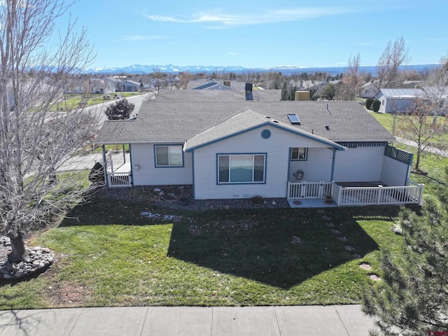 single story home featuring a mountain view, covered porch, roof with shingles, a residential view, and a front lawn