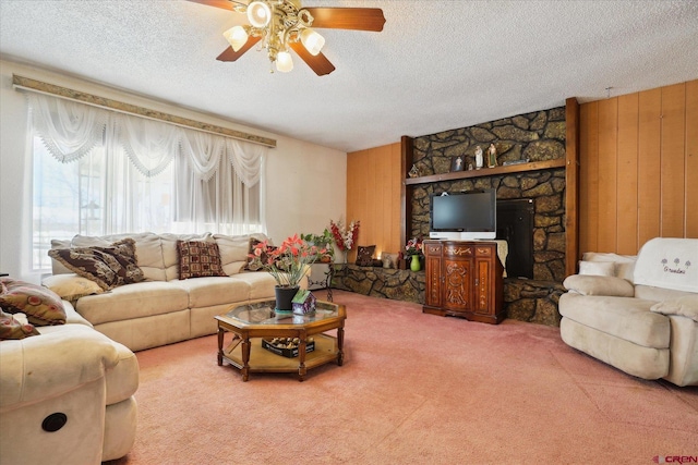 carpeted living area with wood walls, ceiling fan, and a textured ceiling