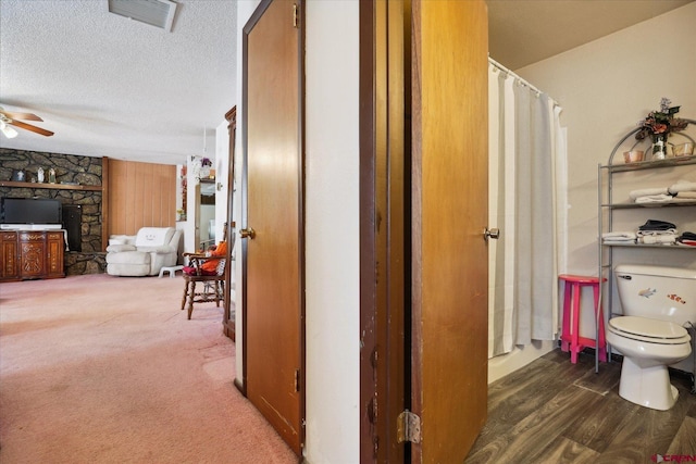 hallway with dark wood-style floors, dark colored carpet, visible vents, and a textured ceiling