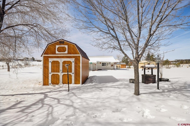 snow covered structure featuring an outbuilding and a storage unit