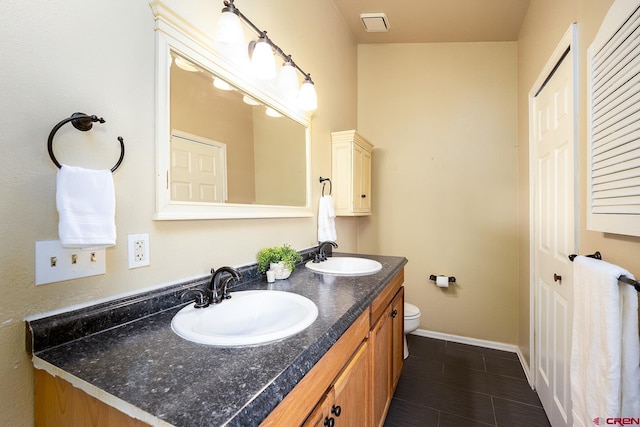 full bath with double vanity, baseboards, toilet, and a sink