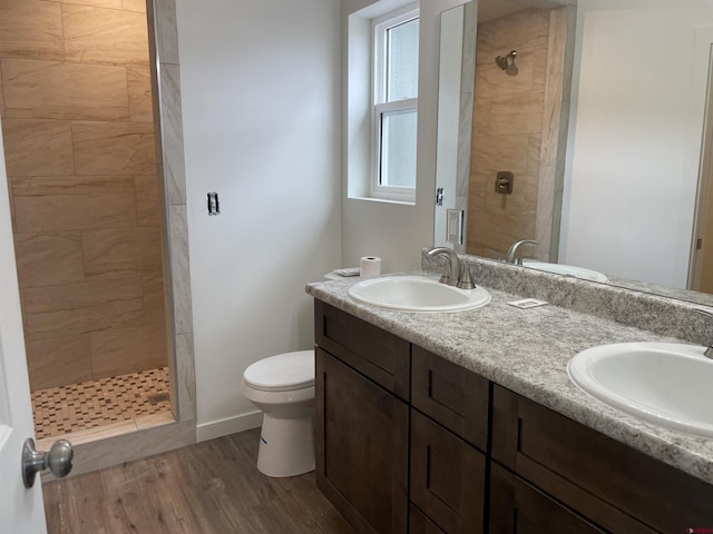 full bath with wood finished floors, tiled shower, and a sink