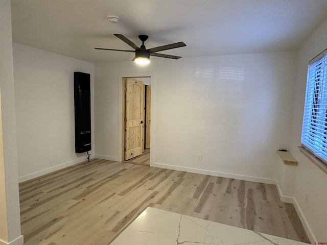 unfurnished room featuring a ceiling fan, baseboards, and light wood finished floors