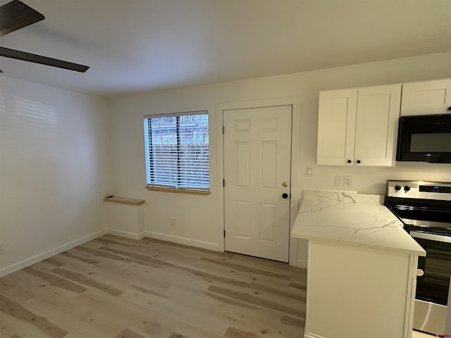 kitchen with black microwave, light stone counters, light wood-style flooring, white cabinets, and stainless steel range with electric cooktop