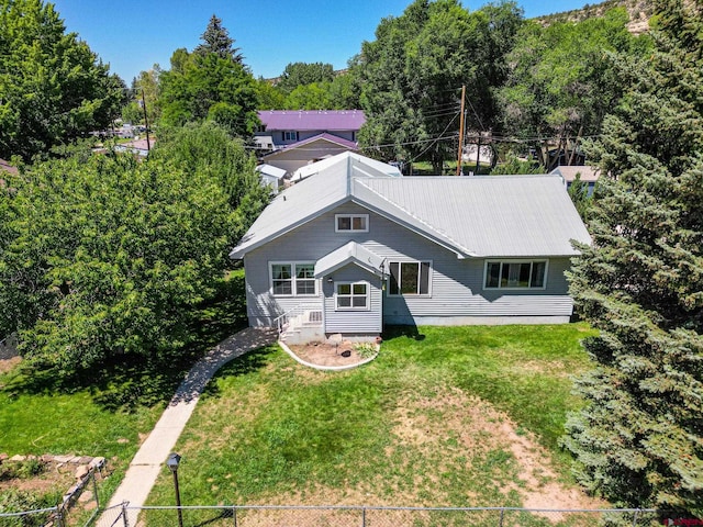 view of front of property with a front yard, metal roof, and fence