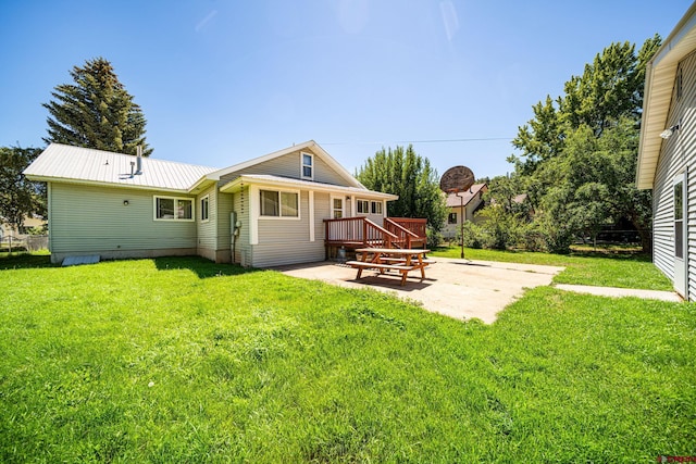 rear view of house featuring a deck, metal roof, a lawn, and a patio