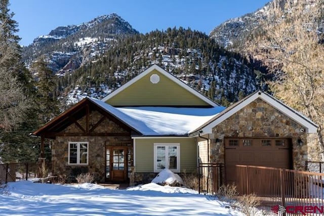 chalet / cabin with a garage, stone siding, fence, and a mountain view