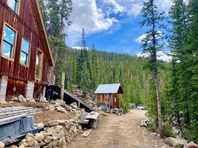 view of yard with an outbuilding, a shed, and a view of trees