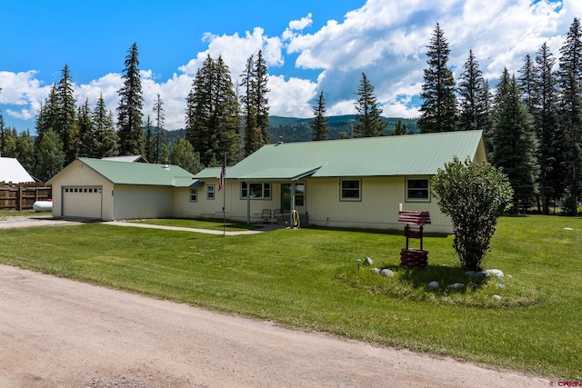 ranch-style house featuring a garage, driveway, a front lawn, and metal roof