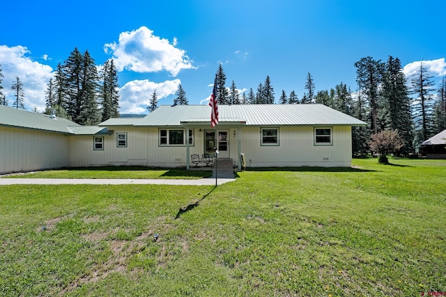 back of property featuring metal roof and a lawn