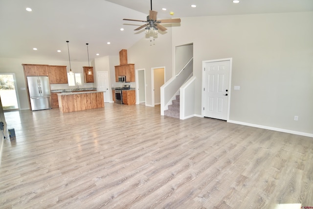 living area featuring stairs, high vaulted ceiling, plenty of natural light, and light wood-style flooring