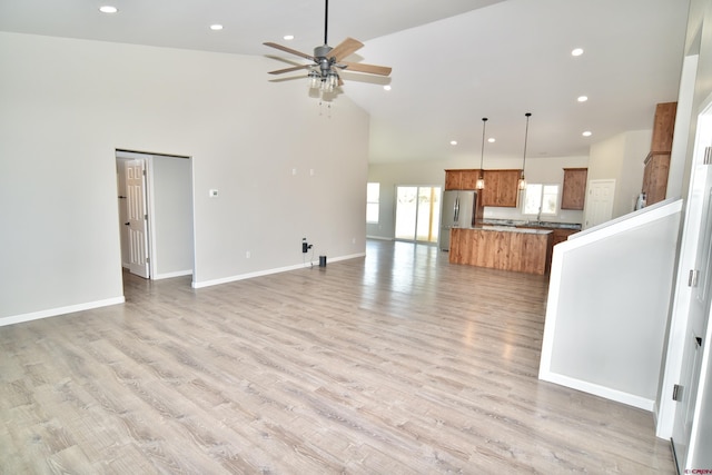 unfurnished living room with light wood finished floors, baseboards, ceiling fan, high vaulted ceiling, and recessed lighting