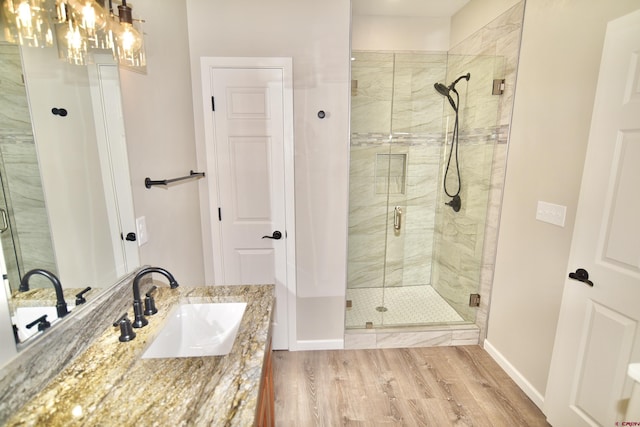 full bath featuring a stall shower, baseboards, wood finished floors, and vanity