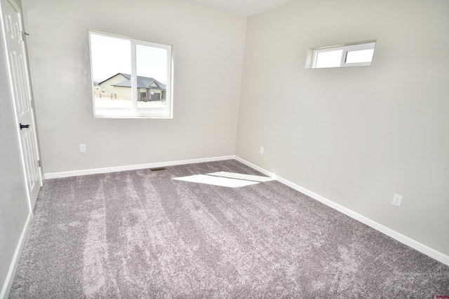 unfurnished room with carpet floors, visible vents, and baseboards