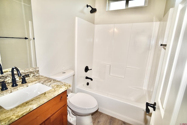 bathroom with toilet, shower / bathing tub combination, wood finished floors, and vanity