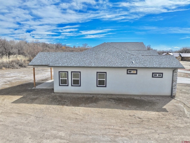 view of home's exterior featuring roof with shingles and stucco siding