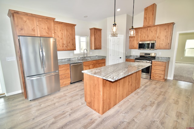 kitchen with light stone counters, pendant lighting, stainless steel appliances, light wood-style flooring, and a kitchen island