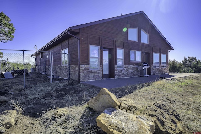 exterior space with stone siding, a patio, and fence