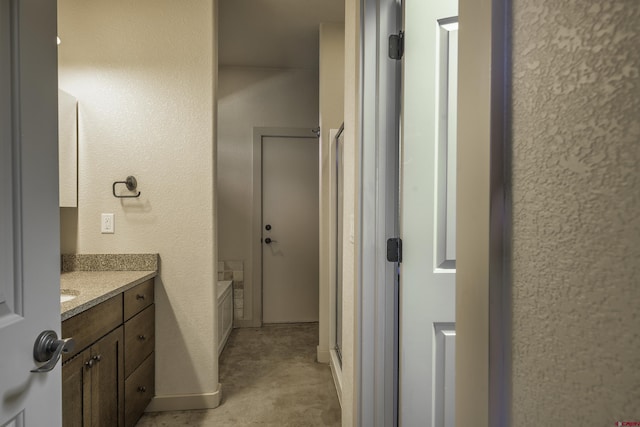 bathroom featuring a textured wall, vanity, and baseboards