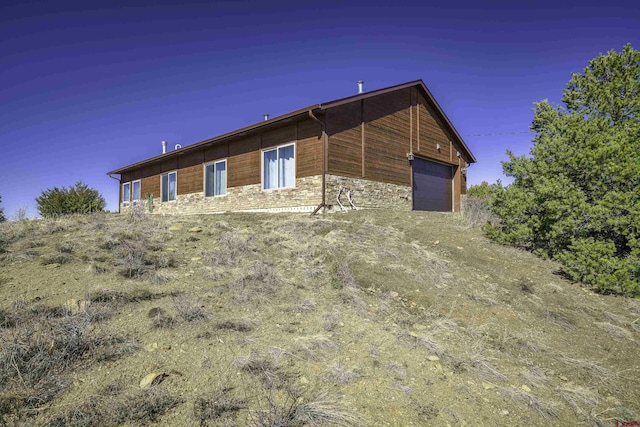 view of side of home with a garage and stone siding