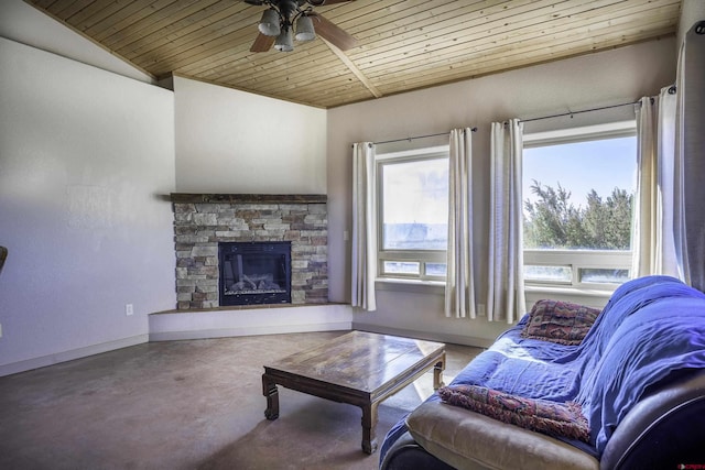 living area with baseboards, wooden ceiling, ceiling fan, a stone fireplace, and concrete floors