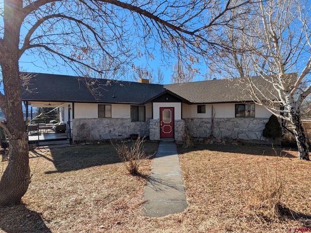 ranch-style house featuring stone siding, a chimney, an attached carport, and roof with shingles