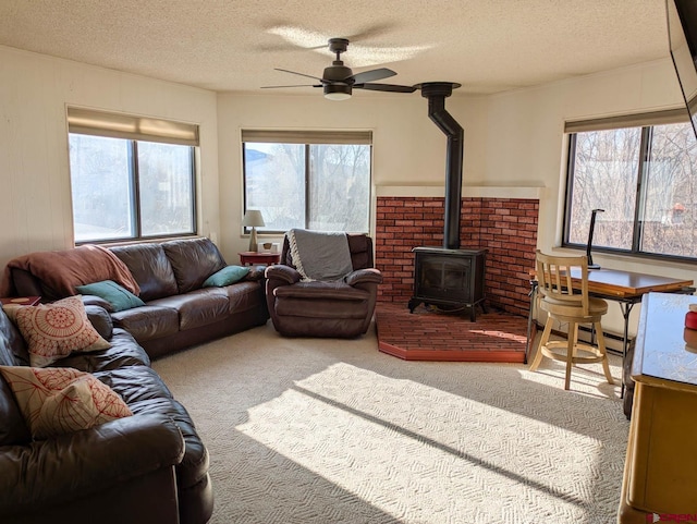 carpeted living area featuring a wood stove, a healthy amount of sunlight, and a textured ceiling