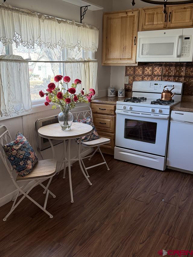 kitchen featuring white appliances, dark wood-style flooring, and tasteful backsplash