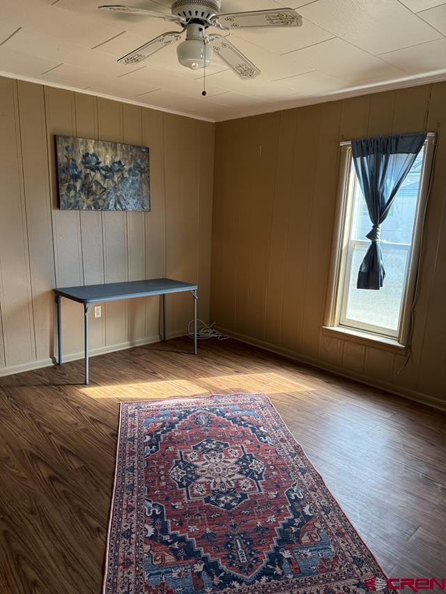 interior space with light wood finished floors, baseboards, ornamental molding, and a ceiling fan