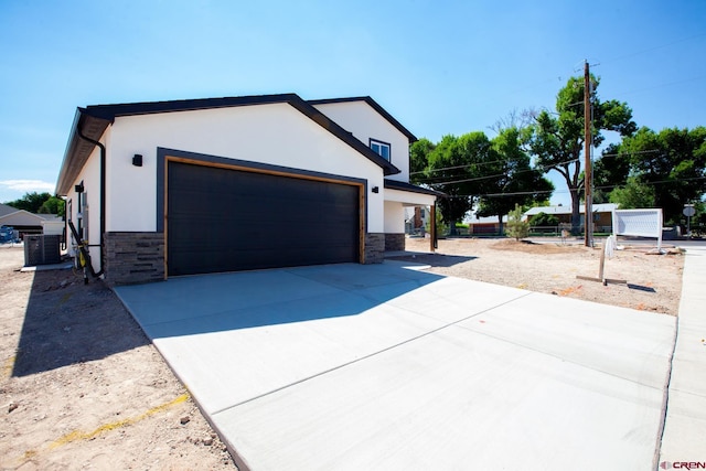 670 Nuvue St Cyprus Floorplan, Cyprus Floorplan, Delta, CO 81416 - view of home's exterior with stone siding, a garage, driveway, and stucco siding