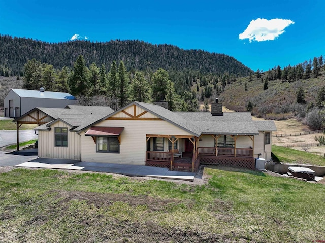 250 Sunset Ln, Durango, CO 81301 - view of front of property with a chimney, board and batten siding, a wooded view, central AC unit, and a front lawn