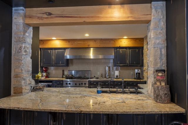 kitchen with decorative backsplash, stainless steel range, beamed ceiling, and wall chimney exhaust hood