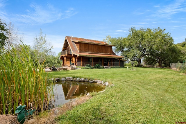 rear view of property with log siding, a garden pond, and a yard