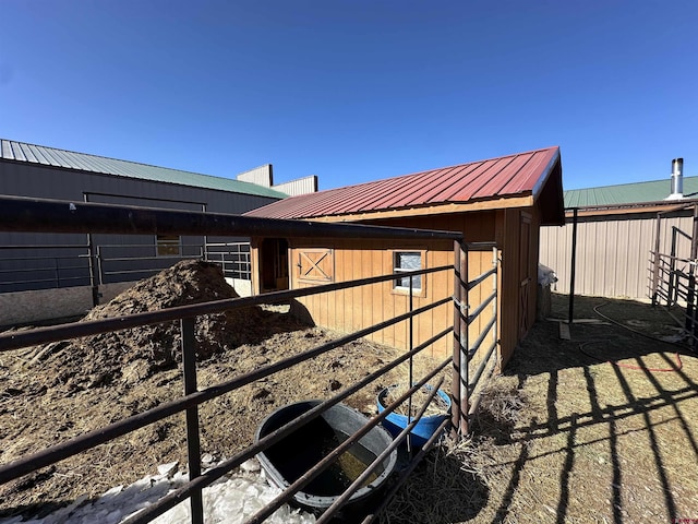 view of side of property featuring metal roof, an outdoor structure, and an exterior structure