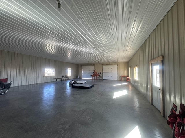 misc room featuring concrete flooring, a garage, and metal wall