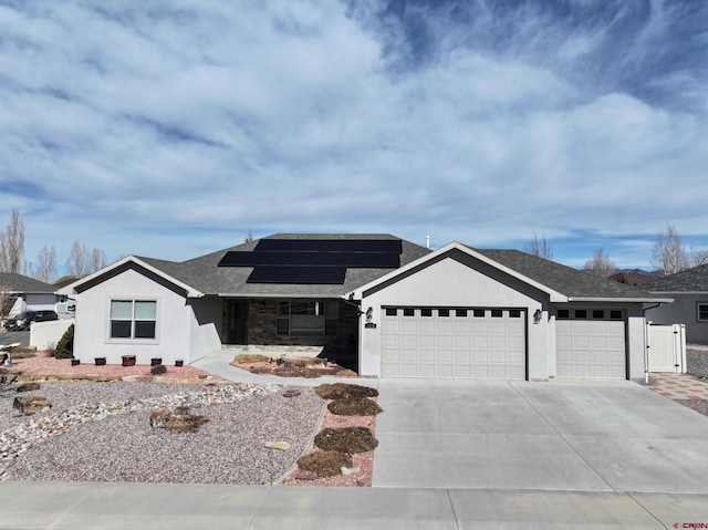 single story home with an attached garage, solar panels, concrete driveway, roof with shingles, and stucco siding