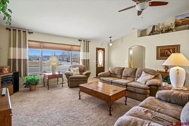 living area featuring baseboards, arched walkways, a ceiling fan, carpet, and vaulted ceiling